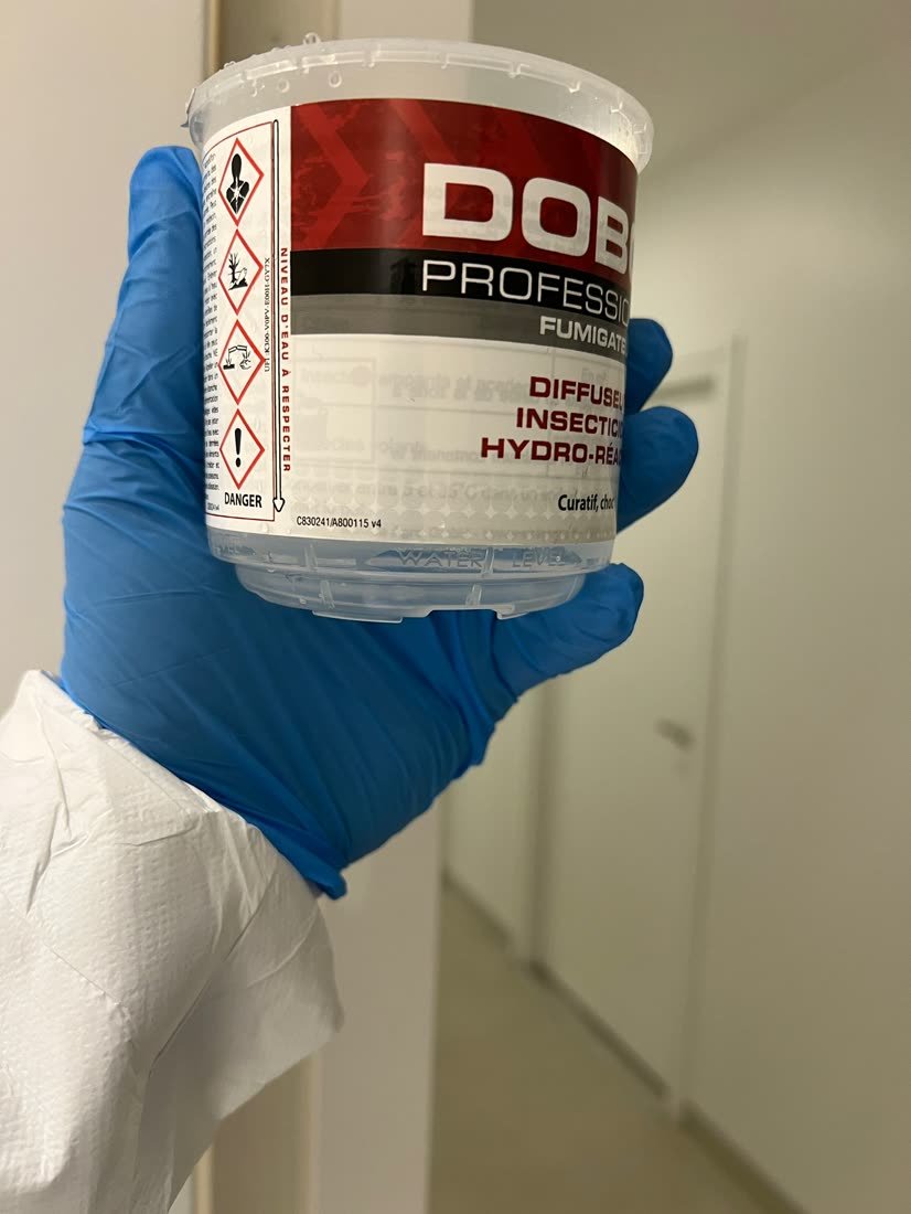 Technicien en combinaison appliquant un fumigène insecticide professionnel lors d'une désinsectisation 3D